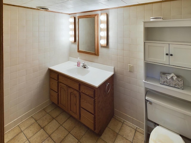 bathroom with toilet, vanity, tile walls, and tile patterned flooring