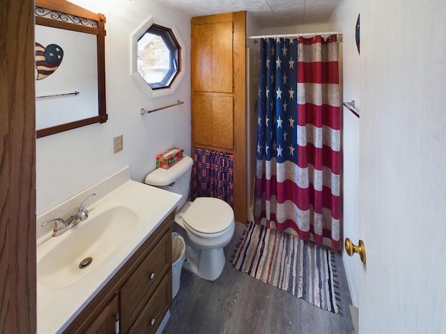 bathroom with walk in shower, hardwood / wood-style floors, vanity, and toilet