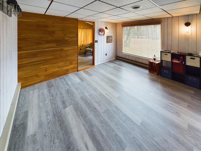 interior space with wood walls, hardwood / wood-style flooring, baseboard heating, and a paneled ceiling