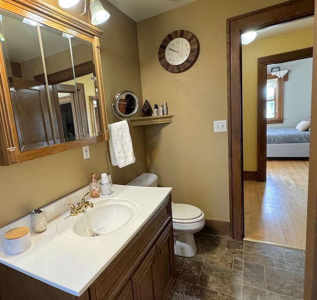 bathroom featuring toilet, vanity, and hardwood / wood-style floors