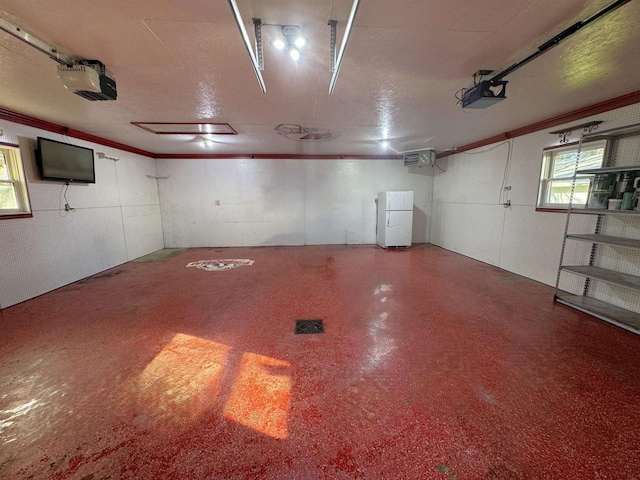 basement with ornamental molding and white refrigerator