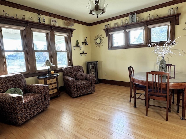 dining space featuring plenty of natural light, a notable chandelier, light wood-type flooring, and ornamental molding