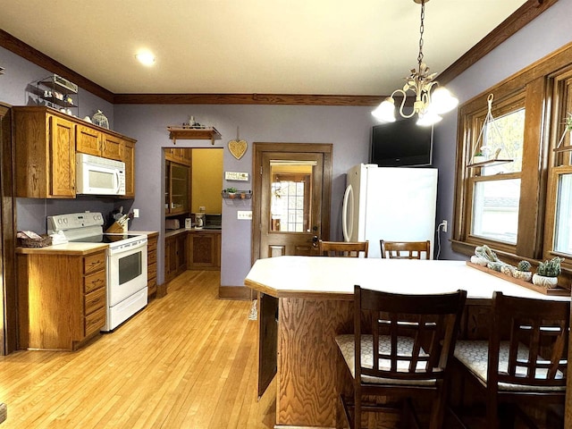 kitchen with white appliances, plenty of natural light, light wood-type flooring, and decorative light fixtures