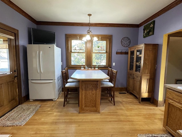 dining room featuring light wood-type flooring, a wealth of natural light, and an inviting chandelier