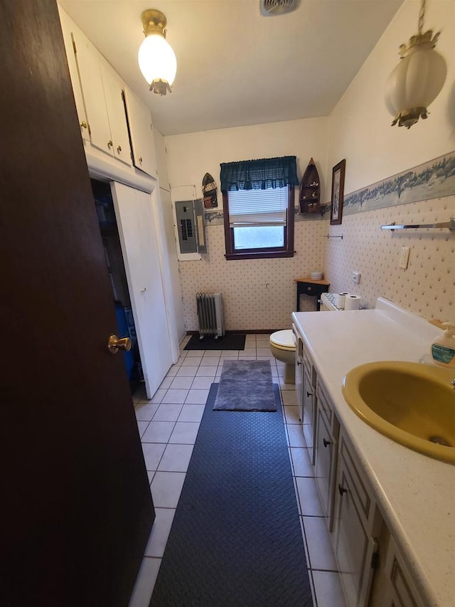 bathroom featuring radiator, electric panel, vanity, tile patterned flooring, and toilet