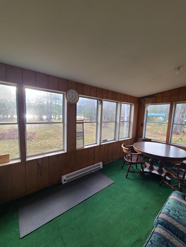 unfurnished sunroom with lofted ceiling, plenty of natural light, and a baseboard heating unit