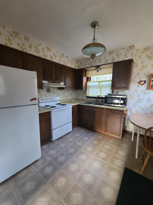 kitchen featuring dark brown cabinetry, decorative light fixtures, sink, and white appliances