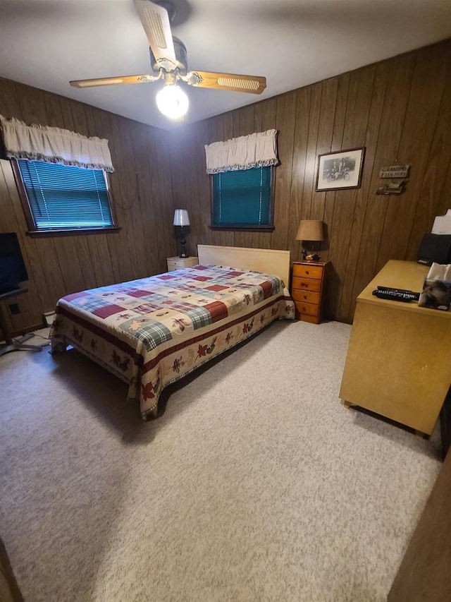 bedroom with wooden walls, carpet flooring, and ceiling fan