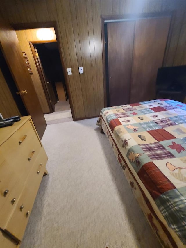 bedroom with wood walls and light colored carpet