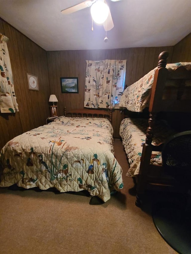 bedroom with carpet, wooden walls, and ceiling fan