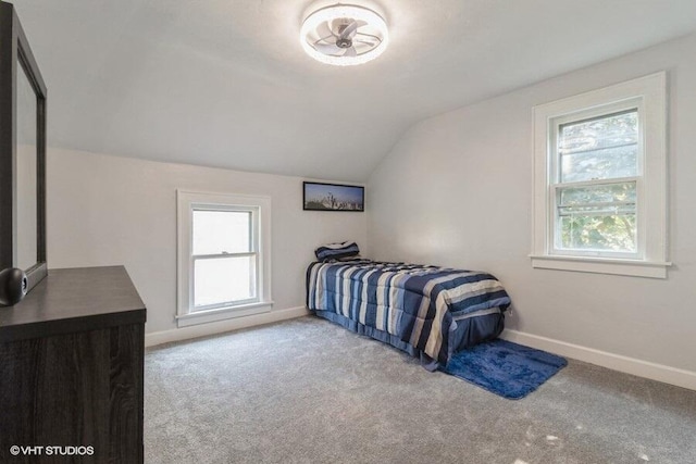 bedroom with light colored carpet, lofted ceiling, and multiple windows