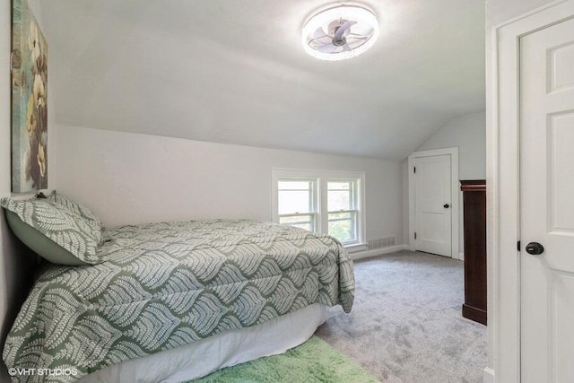 bedroom with light colored carpet and vaulted ceiling