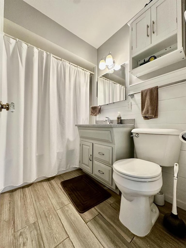 bathroom with a shower with shower curtain, wood-type flooring, vanity, and toilet