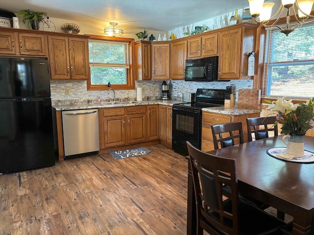 kitchen with black appliances, sink, wood-type flooring, and light stone counters