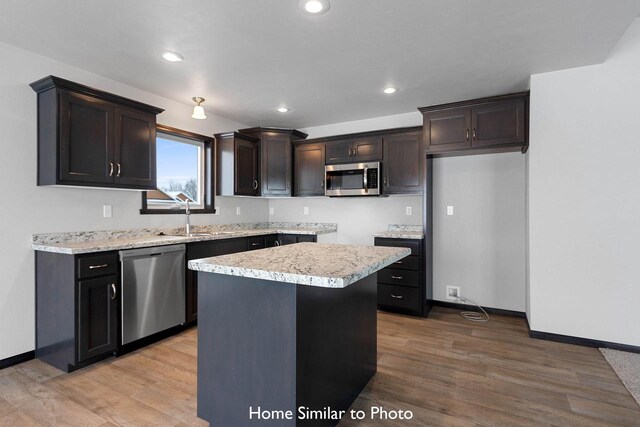 kitchen with sink, a kitchen island, appliances with stainless steel finishes, and light hardwood / wood-style flooring