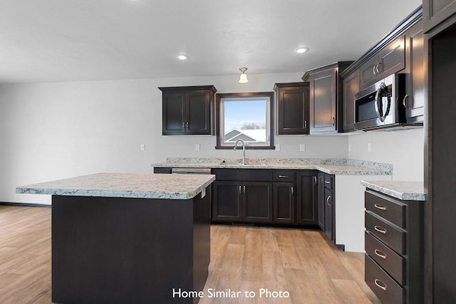 kitchen with sink, light wood-type flooring, and a kitchen island