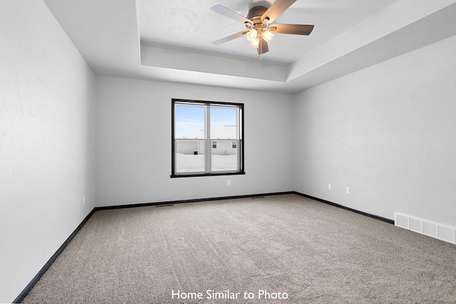 carpeted empty room featuring ceiling fan and a tray ceiling