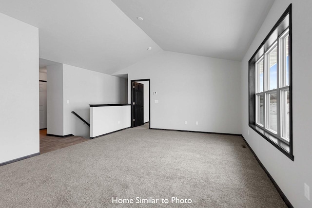 carpeted spare room with lofted ceiling