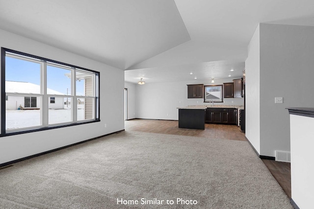 unfurnished living room featuring hardwood / wood-style flooring, sink, and lofted ceiling