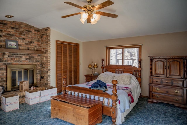 carpeted bedroom featuring ceiling fan, a closet, lofted ceiling, and a brick fireplace