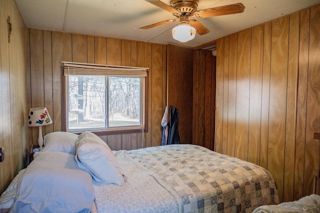 bedroom featuring ceiling fan and wood walls