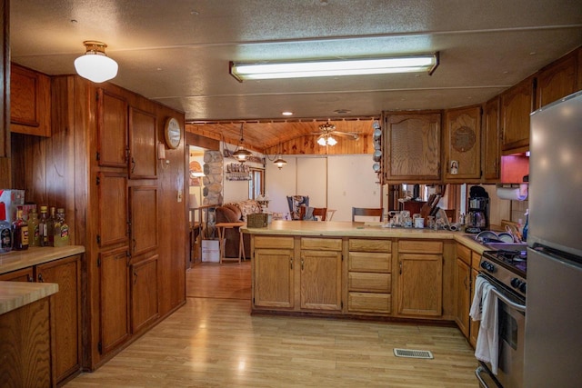 kitchen with pendant lighting, light wood-type flooring, kitchen peninsula, and stainless steel appliances