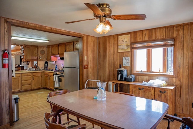 kitchen featuring stainless steel appliances, light hardwood / wood-style floors, and wood walls