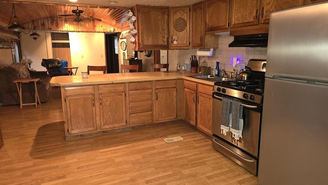 kitchen featuring vaulted ceiling, ceiling fan, appliances with stainless steel finishes, light hardwood / wood-style floors, and kitchen peninsula