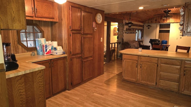 kitchen featuring ceiling fan, wooden ceiling, lofted ceiling, wooden walls, and light wood-type flooring