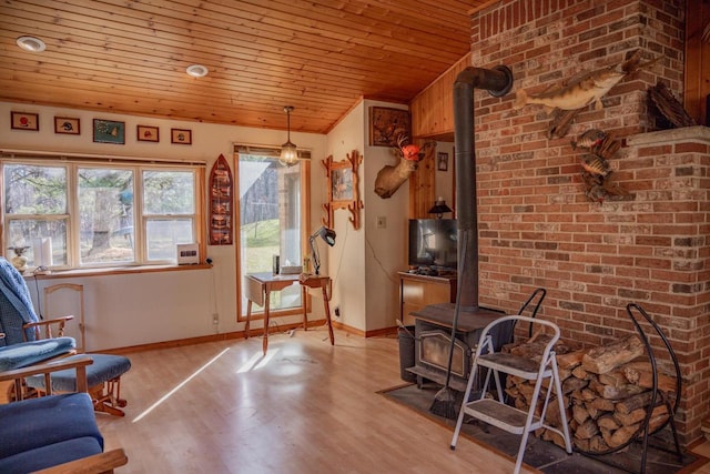 sitting room featuring a wood stove, wood ceiling, and light wood-type flooring