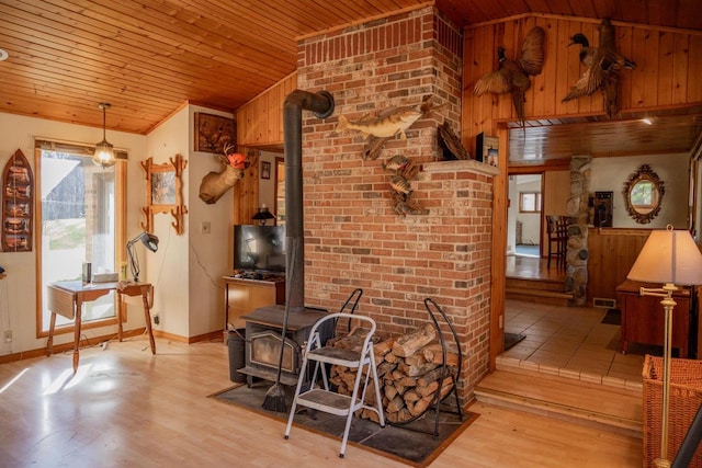 interior space with lofted ceiling, light hardwood / wood-style floors, a wood stove, and wooden ceiling