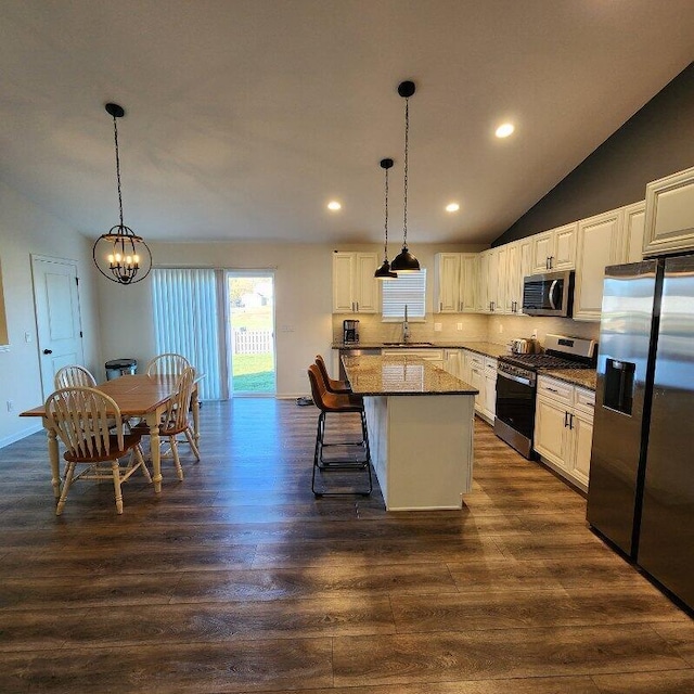 kitchen featuring a center island, dark wood-type flooring, stainless steel appliances, pendant lighting, and lofted ceiling