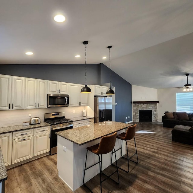 kitchen with wood-type flooring, stainless steel appliances, vaulted ceiling, and a kitchen island