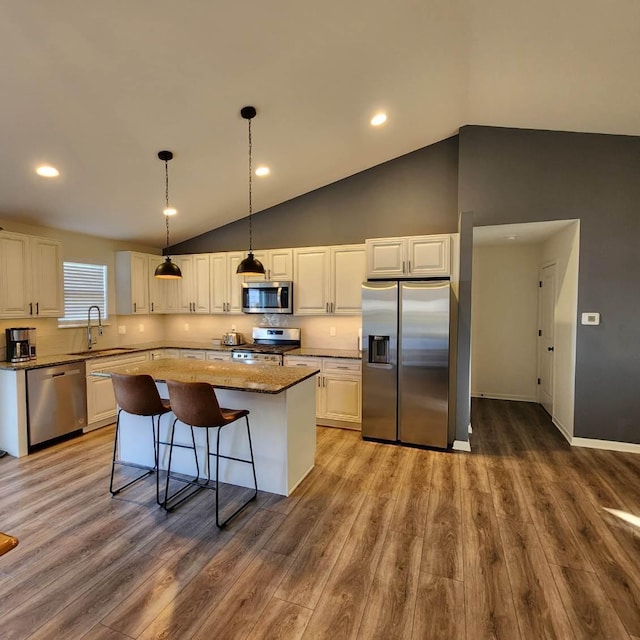 kitchen with light wood-type flooring, stainless steel appliances, a kitchen island, and white cabinetry