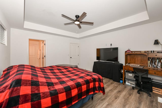 bedroom featuring ceiling fan, a raised ceiling, and wood-type flooring