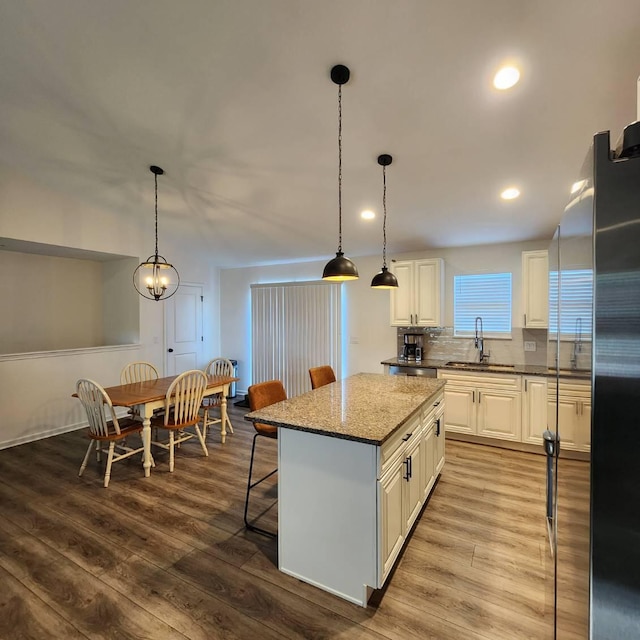 kitchen featuring light wood-type flooring, a center island, hanging light fixtures, and sink