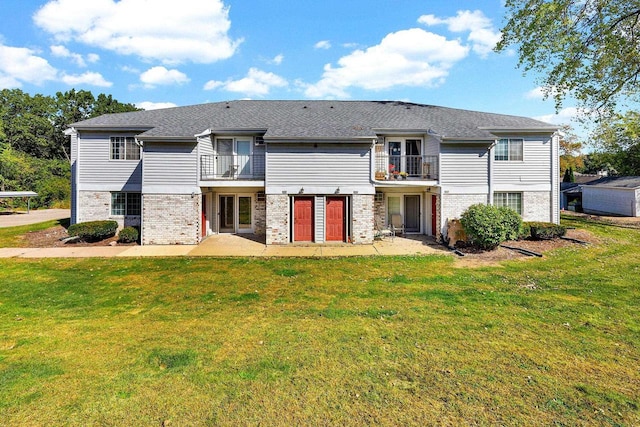 back of property featuring a balcony and a yard