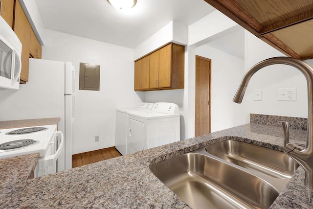 kitchen featuring electric panel, wood-type flooring, sink, washing machine and dryer, and white appliances