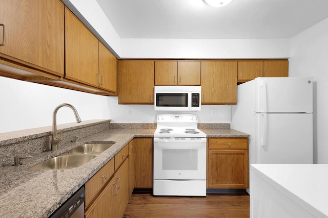 kitchen featuring dark hardwood / wood-style flooring, white appliances, sink, and light stone counters