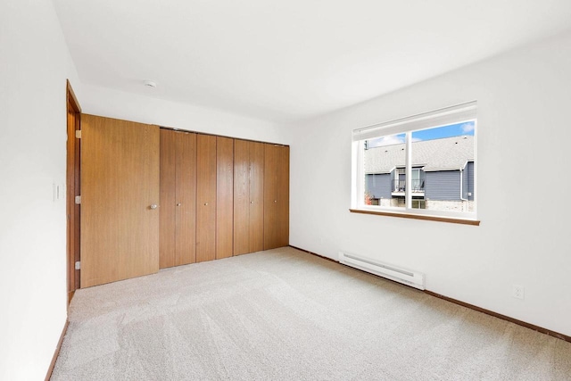 unfurnished bedroom with a closet, light colored carpet, and a baseboard heating unit