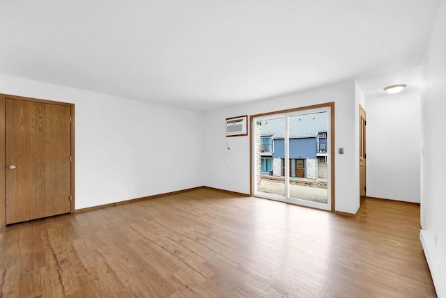 unfurnished room with a baseboard heating unit and light hardwood / wood-style floors