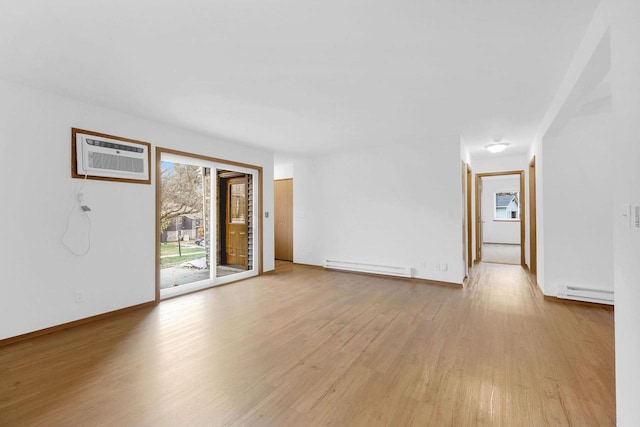 spare room featuring light wood-type flooring, a wall unit AC, and baseboard heating