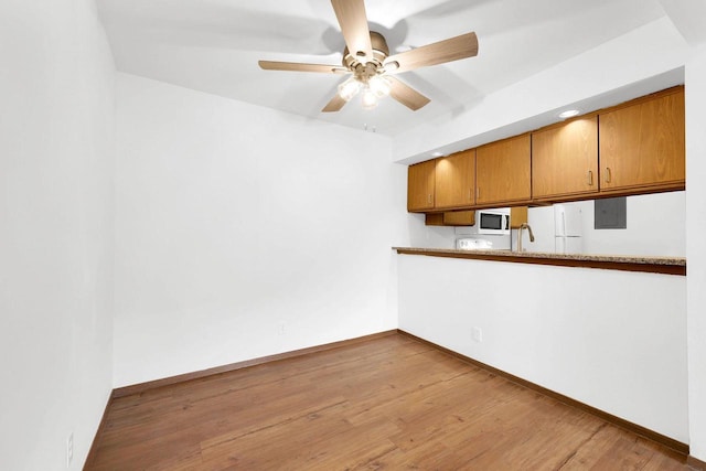 kitchen featuring ceiling fan, white appliances, electric panel, and light hardwood / wood-style floors