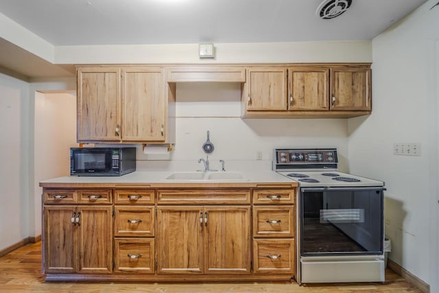 kitchen with light hardwood / wood-style floors, electric range oven, and sink