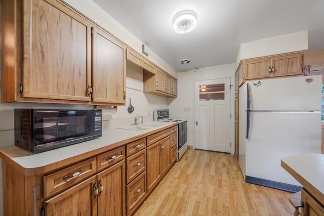 kitchen with light wood-type flooring, white refrigerator, sink, and electric range