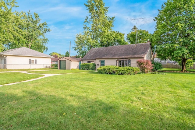 ranch-style house featuring a front yard and a storage shed