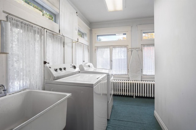 clothes washing area with washing machine and clothes dryer, a wealth of natural light, sink, and radiator