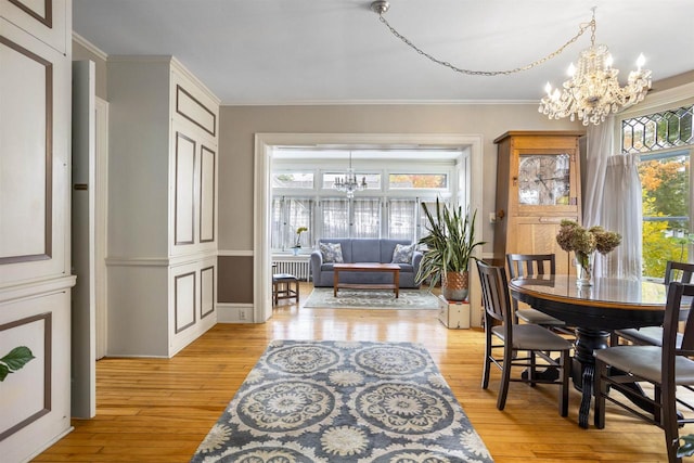 dining area with a wealth of natural light, a chandelier, light hardwood / wood-style floors, and ornamental molding