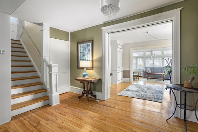 foyer with ornamental molding, light hardwood / wood-style flooring, and an inviting chandelier