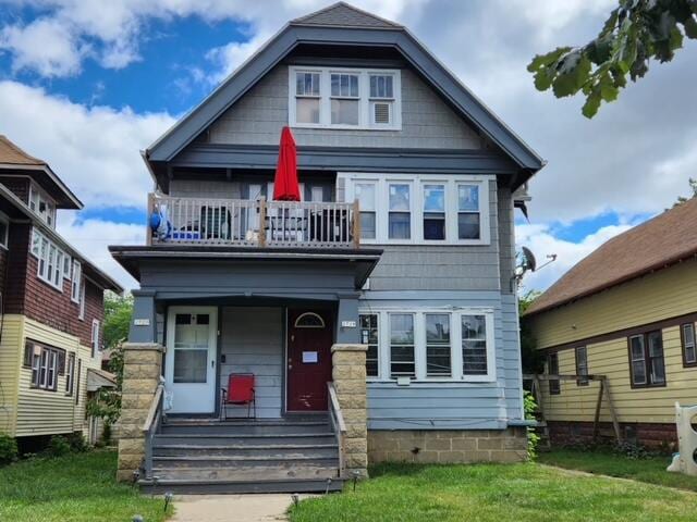 view of front of home with a balcony and a front lawn